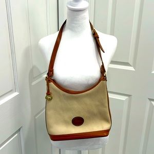 Dooney & Bourke cream leather shoulder bag with tan leather accents.